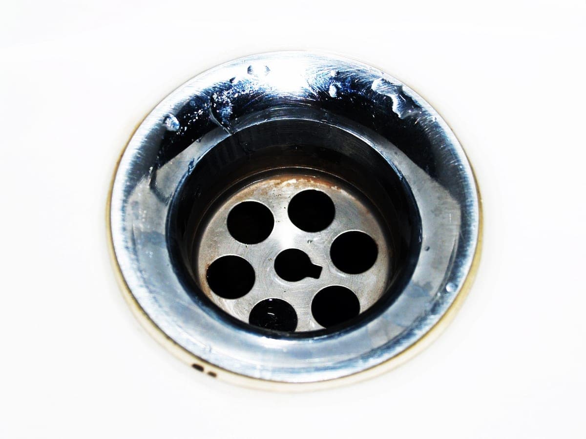 Plumber feeding a drain cleaning cable into a cleanout at a DFW home