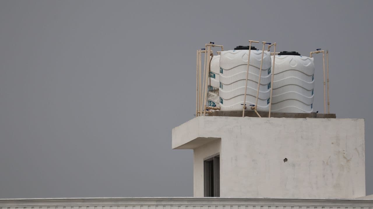 White water treatment tanks plumbed together against a gray sky